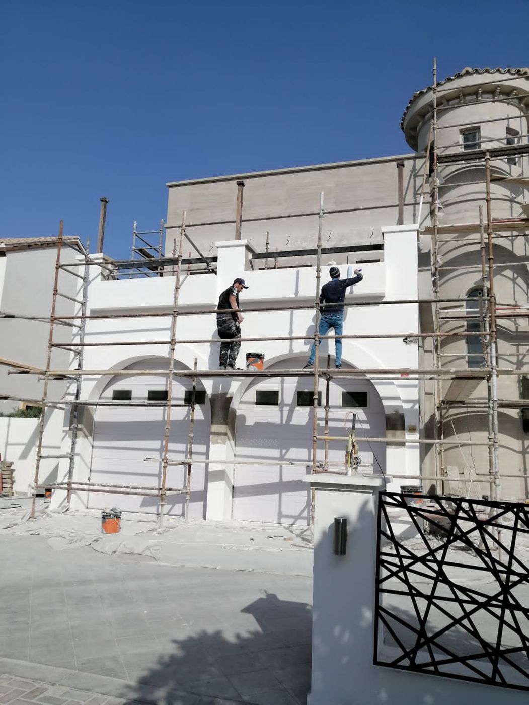 Stone-clad tower and painters finishing the white render on scaffolding