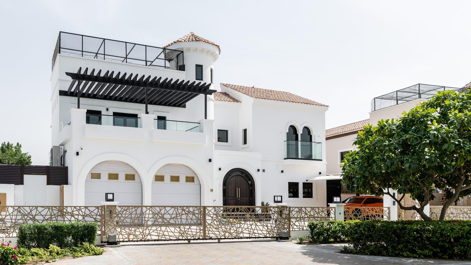 A villa renovated by Cadogan: white render, clay tile roof, arched garage doors and laser-cut gate